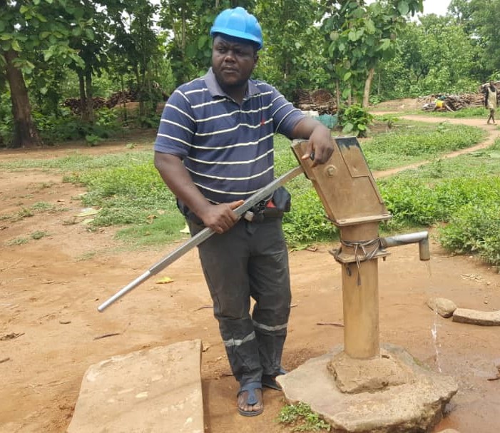 Hosea Apeh standing next to a well being constructed